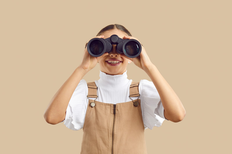 Woman with binoculars to show the importance of being found online with an actively managed Google Business Profile